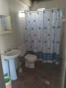 a bathroom with a toilet and a sink and a shower curtain at Hermosa casita con quincho y amplia pileta TODAS LAS COMODIDADES Paz total in Ullún