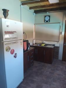 a kitchen with a refrigerator and a clock on the wall at Hermosa casita con quincho y amplia pileta TODAS LAS COMODIDADES Paz total in Ullún