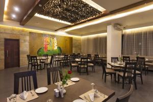 a restaurant with tables and chairs in a room at Hotel Chaitali - Pure Veg in Kolhapur