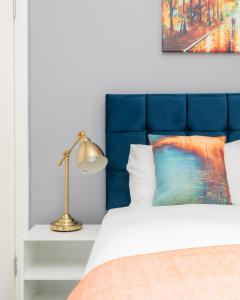 a bed with a blue headboard and a lamp at Homely 3 Bedroom House in Hammersmith in London
