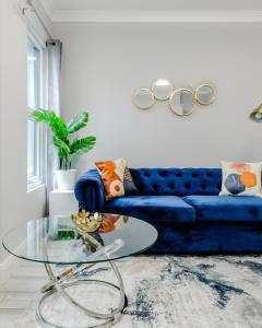 a living room with a blue couch and a glass table at Homely 3 Bedroom House in Hammersmith in London