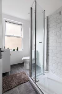 a white bathroom with a shower and a toilet at Homely 3 Bedroom House in Hammersmith in London