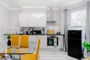 a kitchen with white cabinets and a glass table at Homely 3 Bedroom House in Hammersmith in London