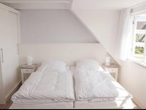 1 dormitorio con 1 cama blanca con sábanas y almohadas blancas en Ual Öömrang Wiartshüs en Norddorf