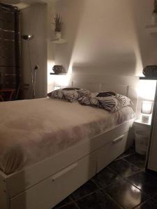 ein weißes Bett in einem Zimmer mit einer Lampe in der Unterkunft Appartement COSY entièrement équipé in Toulouse
