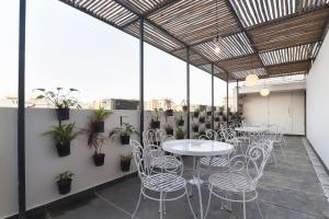 a patio with white tables and chairs and plants at Townhouse Spruce Hotels Bellandur in Bangalore