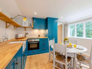 a kitchen with blue cabinets and a white table and a table and chairs at 1 Bed in Sherborne 83499 in Wincanton