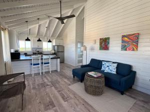 a living room with a blue couch and a kitchen at Barbuda Cottages in Codrington Village