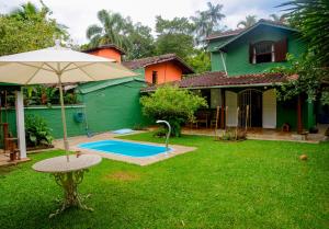 a yard with an umbrella next to a house at Casa Completa c Piscina e 500m da Praia -3 Quartos in São Sebastião