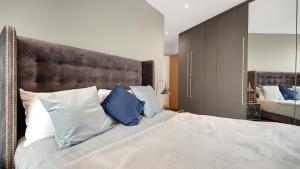a bedroom with a bed with blue and white pillows at Modern and Spacious Penthouse Apartment in Putney with Free Parking in London
