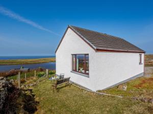 a small white house with a bench in the grass at 2 bed in Achiltibuie 32143 in Achiltibuie
