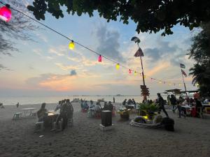 een groep mensen aan tafel op het strand bij Seaview 2 bedroom apartment Mutiara Beach Resort by ISRA in Tangga Batu
