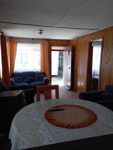 uma sala de estar com uma mesa, cadeiras e janelas em Cabañas Ancud Magico em Ancud