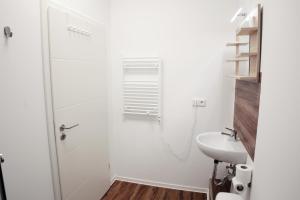 La salle de bains blanche est pourvue d'une douche et d'un lavabo. dans l'établissement Hive Apartments - direkt an der Hannover Messe, à Hanovre
