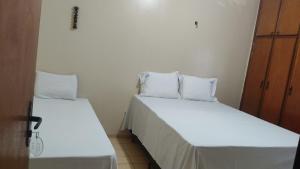 two beds in a room with white sheets and pillows at HOTEL ATLANTA in Paulistana