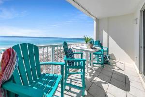 a balcony with blue chairs and a table and the ocean at Gulf Dunes 506 Hello Sunshine in Fort Walton Beach