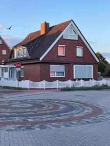 une maison en briques rouges avec une clôture blanche devant elle dans l'établissement Ferienhaus Brandes Wohnung 3, à Norderney