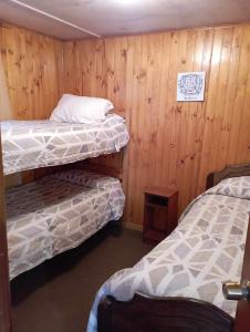 two bunk beds in a room with wooden walls at Cabañas Ancud Magico in Ancud