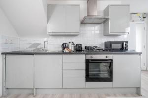 ロンドンにあるTrendy 2bed apartment in Brick Lane - 3rd Floorの白いキッチン(白いキャビネット、コンロ付)