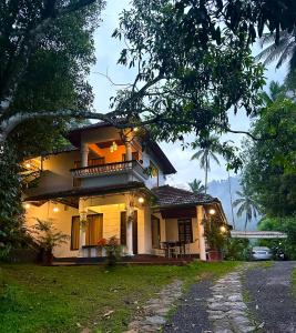 a yellow house with a balcony on a street at Thoppil Homestay Munnar in Munnar