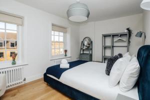 a bedroom with a large bed and two windows at Swan's Nest in Henley on Thames