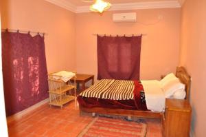 ein Schlafzimmer mit einem Bett und einem Tisch darin in der Unterkunft Gîte d'étape Tamaloute in Bou Drarar