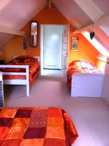 two beds in a room with orange walls at B&B Bij de Boomgaard in Tricht