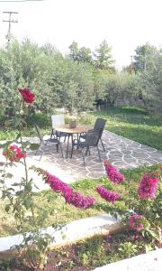 un patio con tavolo, sedie e fiori di The Byzantine Wall House a Isthmia