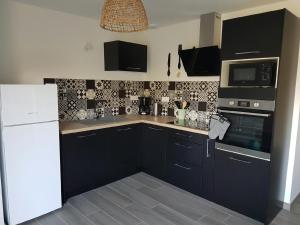 a kitchen with black cabinets and a white refrigerator at La Perle de Dolitéma in Grues