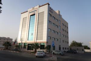 un bâtiment avec deux voitures garées devant lui dans l'établissement فندق اللوتس, à Najran