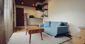ein Wohnzimmer mit einer blauen Couch und einem Couchtisch in der Unterkunft Shikochu Base - Vacation STAY 76591v in Shikokuchuo