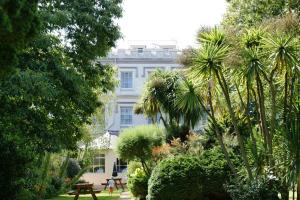 a white building with a lot of trees and plants at Grange Lodge Hotel in Saint Peter Port