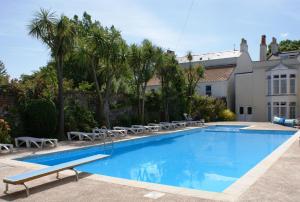 a swimming pool with chairs and a house at Grange Lodge Hotel in Saint Peter Port