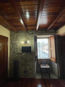 a room with a stone wall with a television and a table at Casa de Costoia in Santiago de Compostela