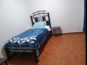 a bed with a blue and white comforter in a room at duplicado in Tlacote el Bajo
