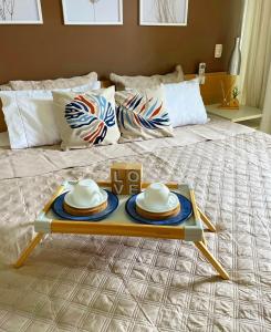 a tray with hats and plates on top of a bed at Flat E311 - Aldeia das águas in Barra do Piraí