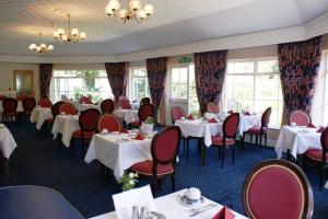 a dining room with tables and chairs and windows at Grange Lodge Hotel in Saint Peter Port