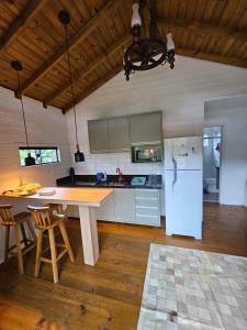 cocina con mesa de madera y nevera en Casa tranquila 500 metros da praia do campeche, en Florianópolis
