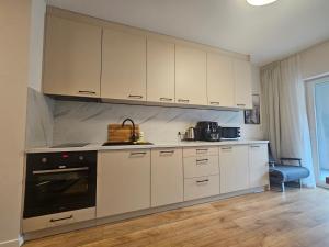 a kitchen with white cabinets and a stove top oven at City Sense - Brand New Apartment Close to the City Center and Main Station in Wrocław