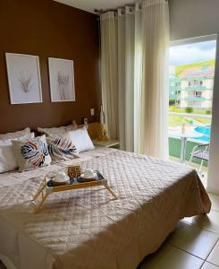 Un dormitorio con una cama con una bandeja de comida. en Flat E311 - Aldeia das águas, en Barra do Piraí