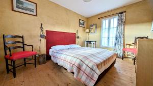 1 dormitorio con 1 cama con cabecero rojo y 2 sillas en Sainte Suzanne gite de LA CHARRETERIE, en Les Baux-de-Breteuil