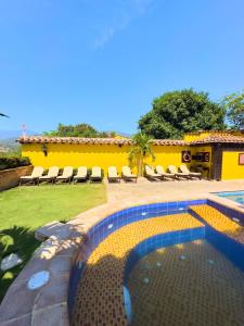 a swimming pool with chairs and a yellow house at Nueva Granada Hotel Colonial -Centro Histórico- in Santa Fe de Antioquia