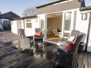 a deck with chairs and a couch on a house at The Cottage at Cromlech Manor Farm in Benllech