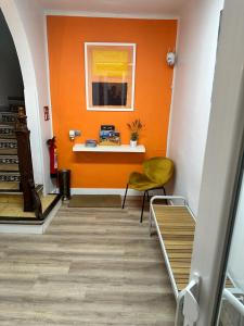 um corredor com uma parede laranja e uma cadeira amarela em Hostal ARS em Puigcerdà