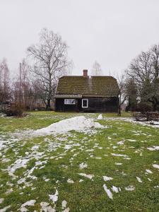 una casa vieja en un campo con nieve en Ziediņi, en Auciems