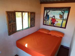 - un lit orange dans une chambre ornée d'une peinture murale dans l'établissement EL KACHI Hospedaje y Restaurante, à Uribia