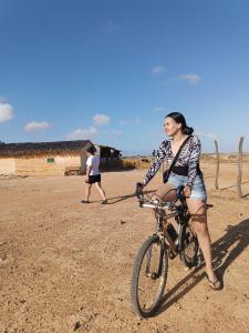 a woman is riding a bike in the dirt at EL KACHI Hospedaje y Restaurante in Uribia