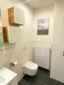 a white bathroom with a toilet and a sink at datKrughuus in Emden