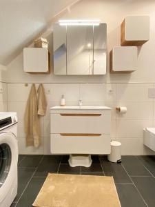 een badkamer met een wastafel en een wasmachine bij datKrughuus in Emden