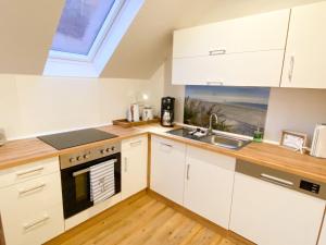 uma cozinha com armários brancos, um lavatório e uma janela em datKrughuus em Emden